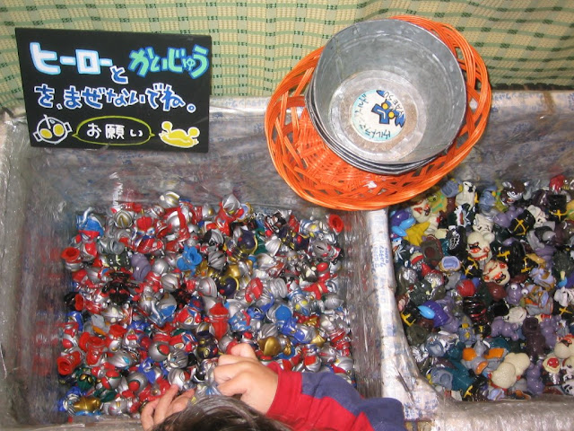 Bins of Ultraman finger puppets at the Ultraman store under Tokyo station. The sign says “Don't mix the heroes and the monsters! Please.”