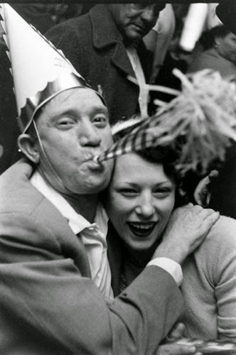 Man blowing a hooter and woman laughing on NYE, sometime in the 40s or 50s I think.