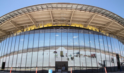 The San Andres Mountains and pieces of construction equipment are reflected in the glass windows of Spaceport America near Upham, N.M., in May. Despite construction delays and difficult working conditions in a remote area of the desert, state officials say New Mexico is committed to seeing the project succeed. Susan Montoya Bryan / AP
