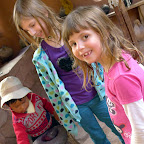 An adorable little boy takes the girls around and shows them how to grind seeds in the mortar for dye.