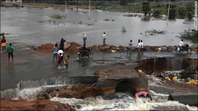 People wade through a flood-damaged road on the outskirts of Hyderabad on 26 October 2013. Photo: Mahesh Kumar A / AP