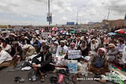The sign held by the old man says: O tyrants! Oppress and be arrogant, but don’t think you can stay forever or escape justice. Do know that your fate will be like that of the Pharaoh. (This refers to the Exodus story told by the Quran in Surat Al Baqarah verse 50 where Pharaoh’s  people drowned in the Red Sea when chasing after Moses.) Friday prayer on 60 Meter Rd, Sana'a, Yemen جمعة الوفاء لأبين  في شارع الستين بصنعاء