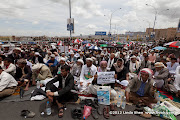 The sign held by the old man says: O tyrants! Oppress and be arrogant, but don’t think you can stay forever or escape justice. Do know that your fate will be like that of the Pharaoh. (This refers to the Exodus story told by the Quran in Surat Al Baqarah verse 50 where Pharaoh’s  people drowned in the Red Sea when chasing after Moses.) Friday prayer on 60 Meter Rd, Sana'a, Yemen جمعة الوفاء لأبين  في شارع الستين بصنعاء