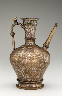 Ewer | Origin:  Syria | Period: June-July 1232  Qasim ibn Ali,Ayyubid period | Details:  Unlike most thirteenth century metalwares from Syria decorated with figural themes, this large and elegant ewer is only embellished with floral motifs and inscriptions. The unusual choice of decoration may reflect the particular taste of the patron, whose name appears on the ewer. He was Shihab al-Din Tughrul, a Turkish commander who served as regent in Aleppo in northern Syria on behalf of Sultan al-Malik al-Aziz (reigned 1216-37) of the Ayyubid dynasty. The ewer was probably reserved for religious ablution rites for which non-representational decoration was considered more appropriate. | Type: Brass with silver inlay | Size: H: 36.7  W: 21.3   D: 21.3  cm | Museum Code: F1955.22 | Photograph and description taken from Freer and the Sackler (Smithsonian) Museums.