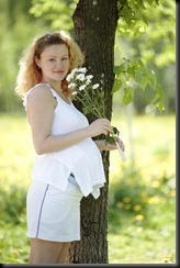 Happy Pregnant Woman with white chrysanthemas outdoors