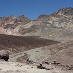 Au premier plan, un rocher. Plus loin des cailloux, des graviers et au fond, des montagnes.