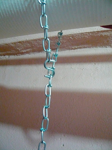 6' lengths of zinc plated chain rated to hold up to 50lbs (much more than the weight of the light fixture) are looped around an insulated water pipe and held in place with easy-on-easy-off 'S' hooks.