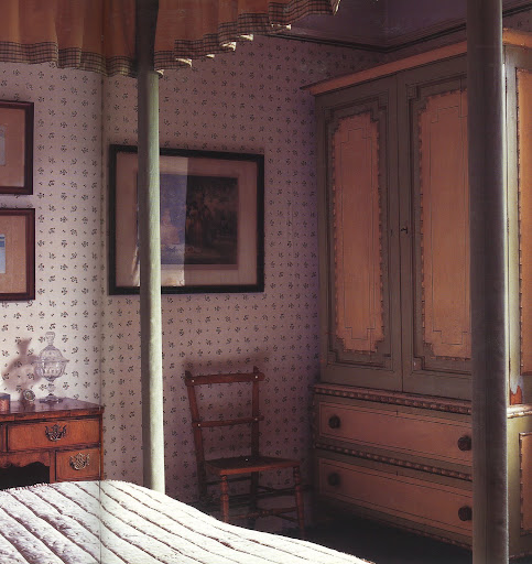 From a quintessential English bed-and-breakfast, the painted wardrobe, cane chair, sweetly patterned wallpaper and four-poster bed work so well together.
