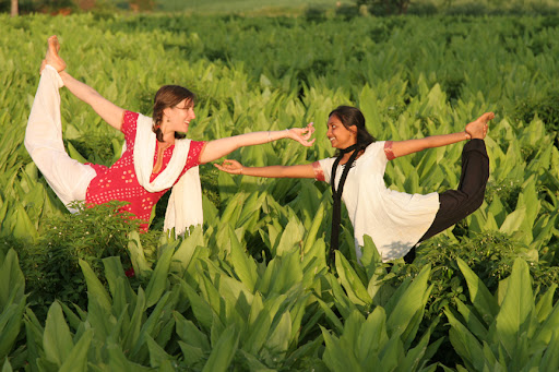 Practicing Natarajasana with Megha in a field.