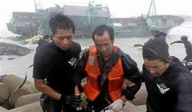 A Chinese fisherman wearing an orange life vest, center, is rescued by South Korean coast guard officers from a Chinese ship in Jeju, South Korea, Tuesday, 28 August 2012. Typhoon Bolaven pounded South Korea with strong winds and heavy rain Tuesday, while the nation's coast guard battled rough seas in a race to rescue fishermen on two Chinese ships that slammed into rocks off the southern coast.  Kim Ho-chun / AP Photo / Yonhap