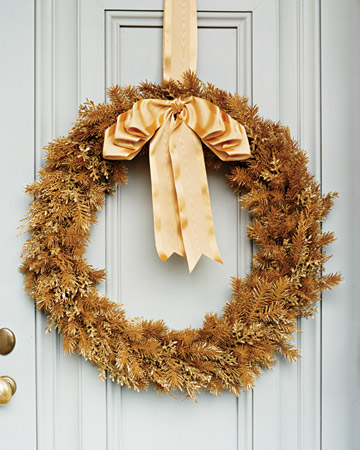 This wreath made from faux gold leaves and branches is a modern take on the traditional wreath.