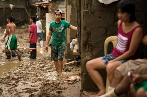 Local residents return to their homes and start to clean up their area from the mud left by the floods at a slum next to a river in San Mateo town, Rizal province, 12 August 2012. The authorities warned on Monday an approaching storm could bring more heavy rain to the capital and surrounding areas that are still reeling from devastating floods that have left 92 dead. Nicolas Asfouri / AFP Photo