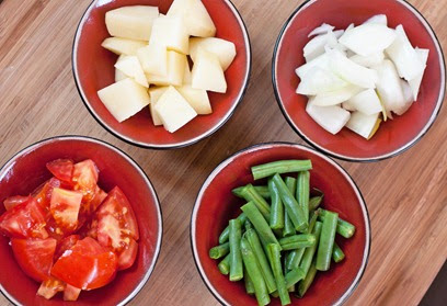 Vegetables chopped for sambar: Cardamom Kitchen Potatoes, onions, tomatoes, and green beans roughly chopped for sambar