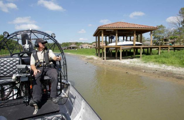 Texas Game Warden, Kevin Creed, patrols in an airboat past boats in landlocked boathouses on Lake Houston Wednesday, Aug. 3, 2011 in Houston. The drought has caused the lake level to drop nearly seven feet. Many of the lakefront homes along Lake Houston now have landlocked boathouses and their waterfront view is now farther away. Photo: Houston Chronicle, Melissa Phillip / AP