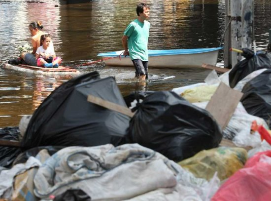Thai residents wade through floodwaters on a street near a pile of garbage in Bangkok, Thailand, 07 November 2011. Bangkok will need to clean up 3 to 4 million tons of garbage once floods covering about 60 per cent of the capital subside while city garbage trucks have not been able to get into some flooded areas, media reports said. NARONG SANGNAK / EPA