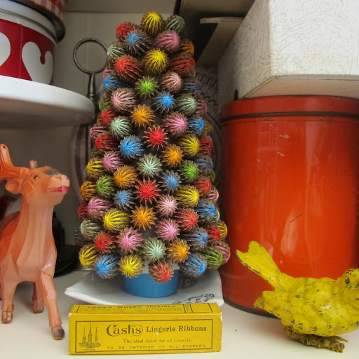 This miniature Christmas tree is made entirely of recycled materials–beechwood nuts covered in colorful thread, a styrofoam cone, and a bottle cap.