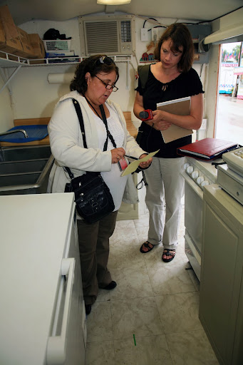 KSMU's Michele Skalicky listens as Lisa Brenneman inspects a vendor's trailer. Photo Credit: Alex Crowder