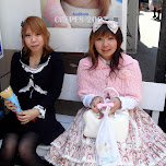 Gothic Lolita and Victorian Lolita girls sitting on a bench eating a crepe in Harajuku, Japan 
