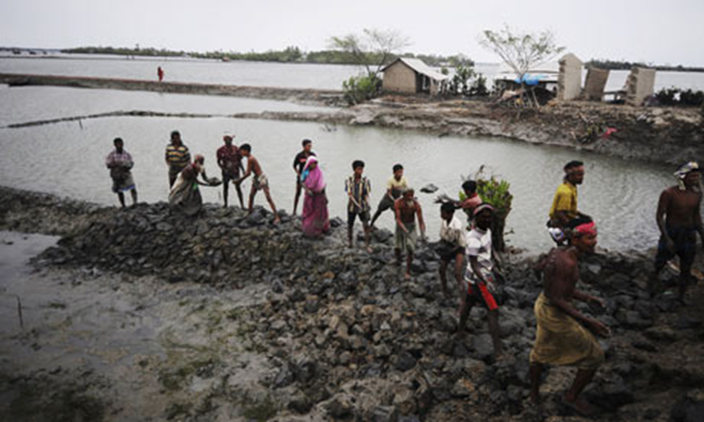 Grappling with solutions: villagers repair a vital flood-protecting embankment after Cyclone Aila struck in 2009. Devastating cyclones, floods and ruined crops have made Bangladesh 'the world's most aware society on climate change'. Munir Uz Zaman / AFP / Getty