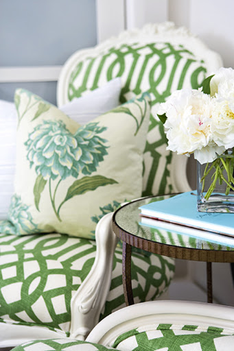 This chair is covered with an emerald latticework pattern that invites in all kinds of cooler florals, such as the pillow displays. Using a prop book to bring a burst of color is an easy decorating trick. (www.krishelmick.com)