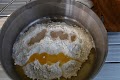 予め、家で分量をはかって混ぜてある、強力粉と砂糖・塩をパウチから出してダッチオーブンへ入れます。このときちょっとだけダッチを加熱し人肌にします。続いて、ドライイースト、溶かしバターをそれぞれ、混ぜないように別の場所に投入