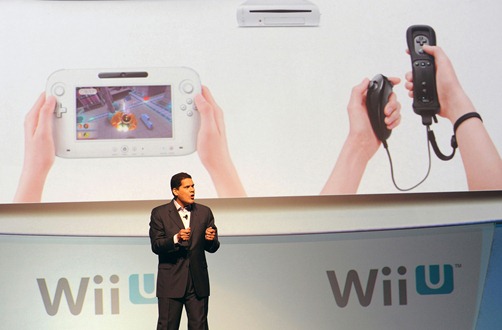 In this photo provided by Nintendo of America, Reggie Fils-Aime, president and coo of Nintendo of America, describes the features of the new Wii U console's controller (left) and the system's (top) compatibility with the current Wii Remote controller during the company's presentation on the opening day of the 2011 Electronic Entertainment Expo (E3), June 7, 2011 in Los Angeles. The E3 is the video game industry's premier trade show. (Photo by Nintendo of America, Bob Riha, Jr.)  No Sales