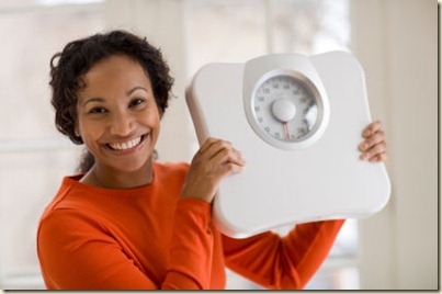 Happy Black woman holding scale