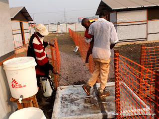 De gauche à droite, un préposé de MSF Belgique désinfecte un homme transportant son enfant, victime de l’épidémie du choléra ce 25/07/2011 dans un centre médical des prises en charge des malades à Kinshasa. Radio Okapi/ Ph. John Bompengo
