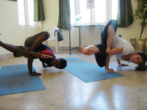 Practicing Side Crow with yoga student Siddu at Deenabandhu.