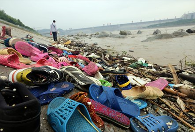 Shoes and other debris are swept ashore in Yichang, Central China's Hubei Province, on Sunday, 21 July 2013. Flood water was discharged from the Three Gorges Dam, a gigantic hydropower project on the Yangtze River, on Sunday. The Yangtze River braced for its largest flood peak so far this year due to continuous rainfall upstream. Photo: CFP