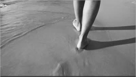 stock-footage-women-walks-on-the-beach-leaving-footprints-in-the-sand