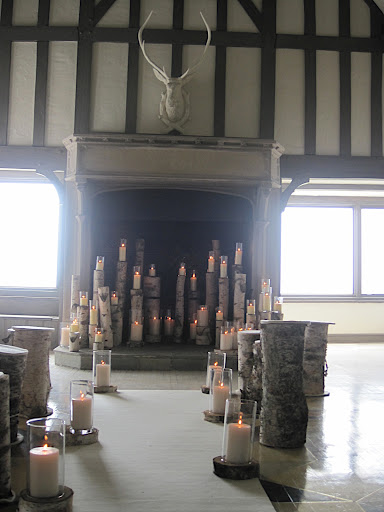 Pillar candles in hurricane glasses sat atop log slices.