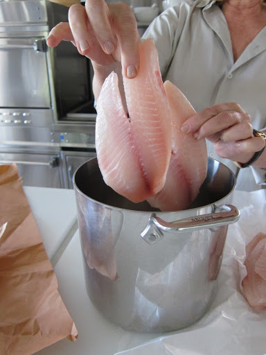 Martha places the tilapia in a large pot.