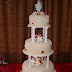 Nº142: Terminación en fondant extendido marfil, azahares de azucar y florcitas pequeñas en rojo, montaje tradicional sobre pilares.