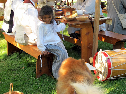 Why hello, little miss!  May I partake in some of your meal?  I am but a simple peasant dog, begging for scraps!