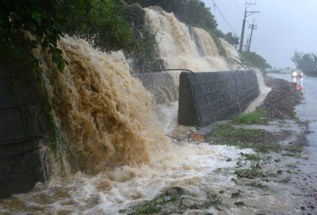 A car drives past waterfalls created by the run-off of rain from Typhoon Usagi near the Taiwanese town of Hengtsun, on 21 September 2013. Photo: Sam Yeh / AFP