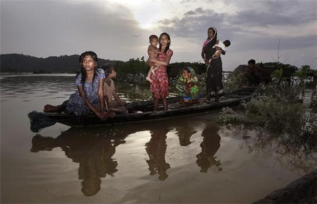 A flood-affected family sits on a boat surrounded with floodwaters at Tin Tukra about 35 kilometers (22 miles) east of Gauhati, India, Saturday, 30 June 2012. Officials in northeastern India are on alert for poachers after surging flood waters forced endangered rhinos, Asiatic elephants, a variety of deer and other animals. Anupam Nath / AP Photo