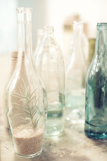 A mixture of colored glass bottles filled with sand and beach plants played up the theme. A mixture of colored glass bottles filled with sand and beach plants played up the theme.