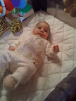 Hanging out in the bassinet. You can see bits of the toys that are hung above it.