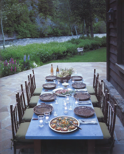 A cozy summer meal is set on the terrace on the edge of the Big Wood River shaded by the Bald Mountains -- complete with local farmers' market cuisine and American rustic furniture. A cozy summer meal is set on the terrace on the edge of the Big Wood River shaded by the Bald Mountains -- complete with local farmers' market cuisine and American rustic furniture.