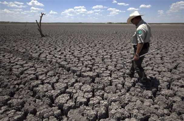 In this 3 August 2011 file photo, Texas State Park police officer Thomas Bigham walks across the cracked lake bed of O.C. Fisher Lake, in San Angelo, Texas. The impacts of record-breaking heat and years of low or no rainfall can be felt years after the dry spell passes, and in February 2014, Texas is now struggling with some of the worst impacts of a historic one-year drought that crippled the state's lakes, agriculture and water supplies. More than 50 percent of Texas remains in drought despite more consistent rainfall in the past two years, climatologists said. Photo: Tony Gutierrez / AP
