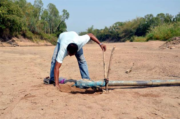 A man in northern Thailand digs around a water intake in a dry riverbed, 3 May 2012. Many parts of Thailand suffer from heat and drought, authorities have launched rainmaking operations in the lower northern region to assist farmers. nationmultimedia.com