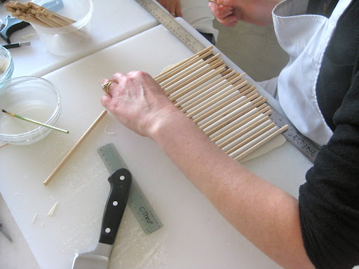 Here, she's completing the first step and measuring the width of the gum paste to fit the different tiers of the cake.