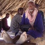 chief under hut with radio.JPG