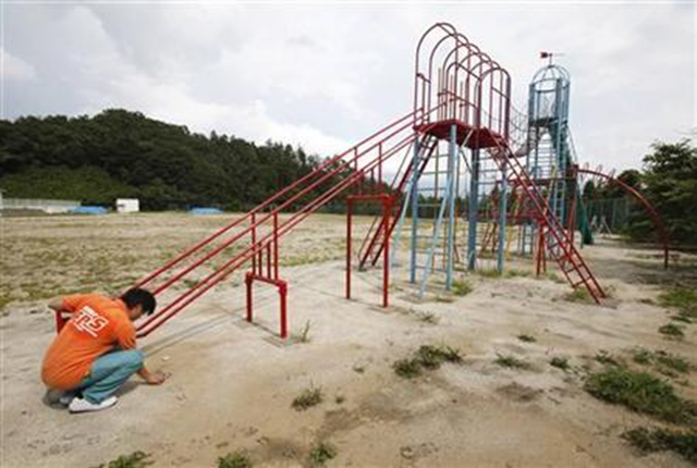 A worker of an office cleaning company monitors the level of radiation at a playground of an elementary school in Fukushima, northern Japan August 6, 2011. Yuriko Nakao / Reuters