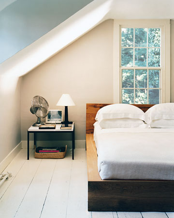 The wide-planked wooden floor's white sheen, along with the light walls and sparse decor, helps offset the dormers in this low-ceilinged guest room.