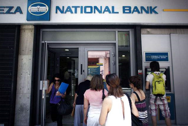 Customers queue to enter a National Bank of Greece SA branch in Athens. An accelerating flight of deposits from banks in four European countries is jeopardizing the renewal of economic growth and undermining a main tenet of the common currency: an integrated financial system.  Angelos Tzortzinis / Bloomberg