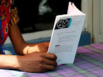Des mains d'une lectrice tenant un livre. Radio Okapi
