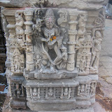 Chamunda/Kali, shown here with eight hands. Lower two hands are clasped in front, as in other statues we saw earlier. There is munda-garland (human skull garland) around her body. She is also holding a human skull in one of her hand. A human figure is shown lying on the ground, but the goddess is not shown standing over this, so can it be Shiva?