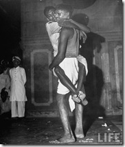Man carrying another man as they wait in railroad station trying to escape city after bloody rioting between Hindus and Muslims
